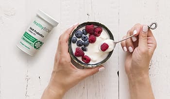 Healthy yogurt with berries in a bowl on a table with bottle of probiotics