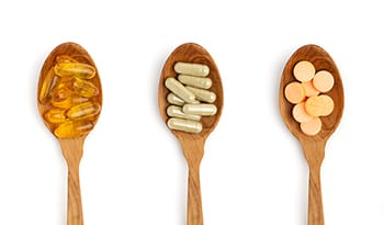 Omega-3s, probiotics, collagen supplements in wooden spoons on white background