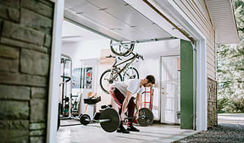 A man working out and lifting weights in his home garage.