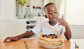 Boy eating waffles at the kitchen table at home