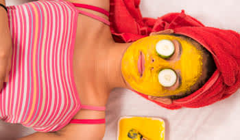 woman relaxing with a turmeric mask on her face and cucumber slices on her eyes