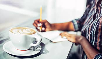 woman sitting with a latte and planning out her self-care