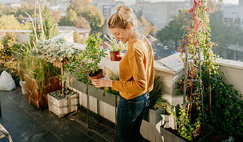 Young woman taking care of her plants outside on a rooftop garden