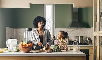 Mother and daughter cooking healthy nutritious meal in kitchen