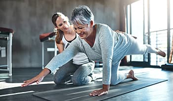 Female trainer working with client on yoga mat 