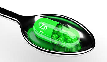 Zinc supplement in spoon on white background