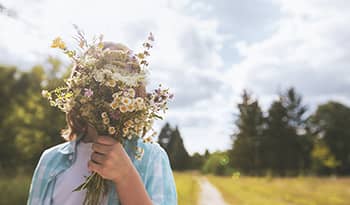 Child holding bouquet of flowers outside in nature