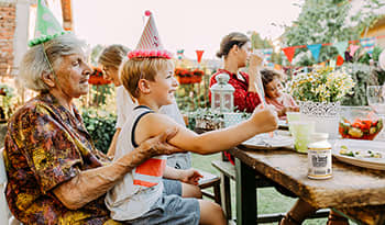 Outdoor family party with grandmother and grandson eating together