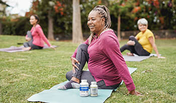 Healthy mature women doing yoga outside on grass