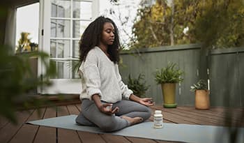 Young woman meditating outside in the garden on yoga mat