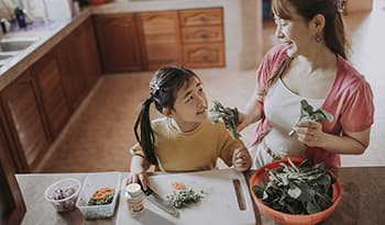 Asian mother and daughter cooking healthy meal in the kitchen