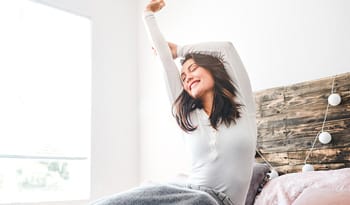 woman stretching in bed after waking up from beauty sleep