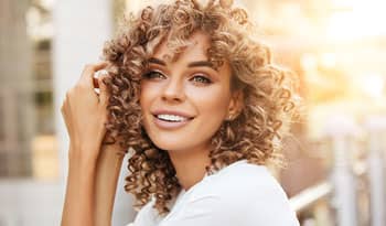 woman with curly hair thinking about the different types of hair masks she can use