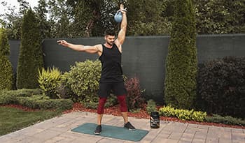Male athlete working out in backyard with kettlebell