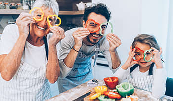 Happy multi-generation family cutting peppers and cooking dinner in the kitchen