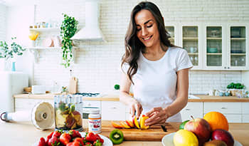 Young woman making a fruit smoothie in the kitchen