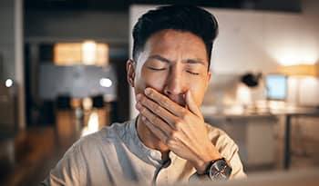 Asian male working at home yawning