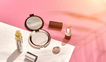 flat lay summer makeup against sunset gradient background