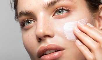 portrait of woman applying makeup primer to her face