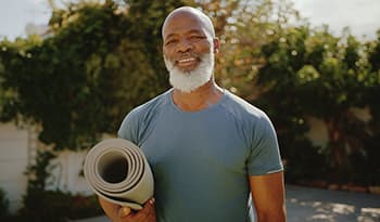 Healthy older man standing outside before a yoga session in his backyard