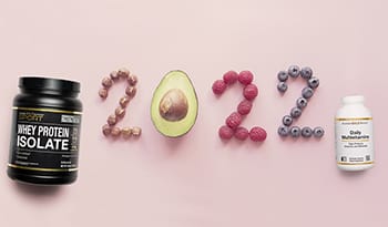 2022 spelled out with nuts and fruit along with supplements on pink background