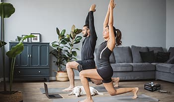 Healthy fit couple working out doing yoga at home