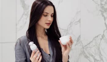 woman looking at two skincare products wondering if she should mix them