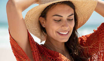 woman at the beach wearing a sun hat to prevent sun burn