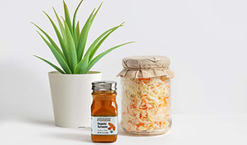 Turmeric spice and jar of turmeric sauerkraut with plant on table
