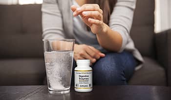 Digestive enzymes supplement and glass of water on table