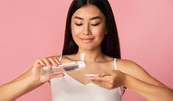 asian woman pouring her favorite k-beauty toner on a cotton pad