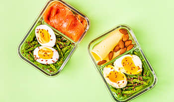 Healthy keto lunchbox with eggs, salmon asparagus, flax seeds