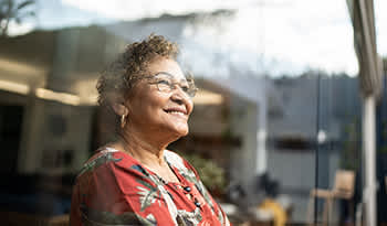 Mature woman with glasses smiling looking out the window