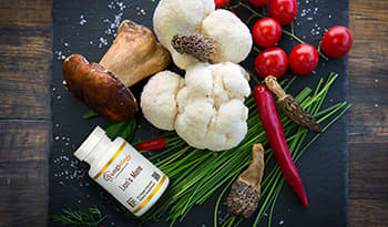 Lion's mane mushrooms on cutting board with other vegetables and supplement bottle