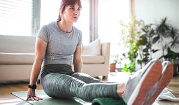 Young active woman using foam roller at home