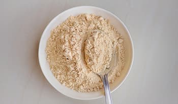 Maca root powder supplement in bowl with spoon