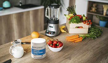 Kitchen counter with smoothie ingredients like collagen, vegetables, milk, and fruit