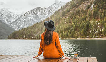 Woman sitting on dock looking at the mountains with vitamins and supplements