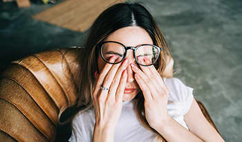 Woman with glasses rubbing her eyes