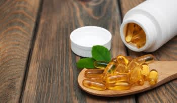 Fish Oil omega-3 fatty acid capsules and bottle on wooden table