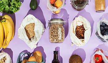 Healthy nuts, seeds, and grocery items on a purple background 