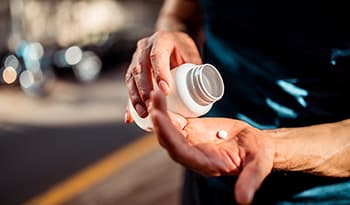 Man pouring vitamin or supplement into hand