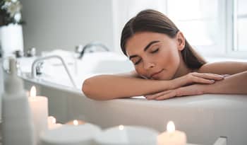 woman enjoying a soak in the bathtub with her favorite self-care products