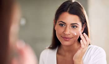 woman applying moisturizer with probiotics to her skin