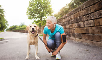 woman bending down smiling at her dog outdoors