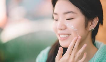 asian woman using rice-based k-beauty products on her face