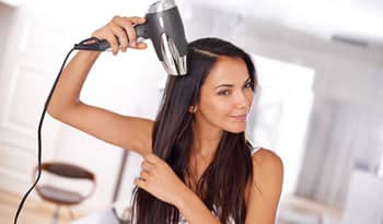 woman blow drying her hair at home