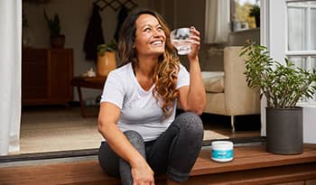 Woman drinking glass of water sitting on porch