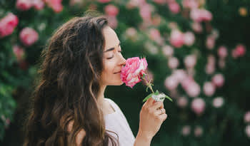 woman smelling a rose in a garden