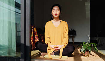 Peaceful Asian woman sitting in the sun meditating